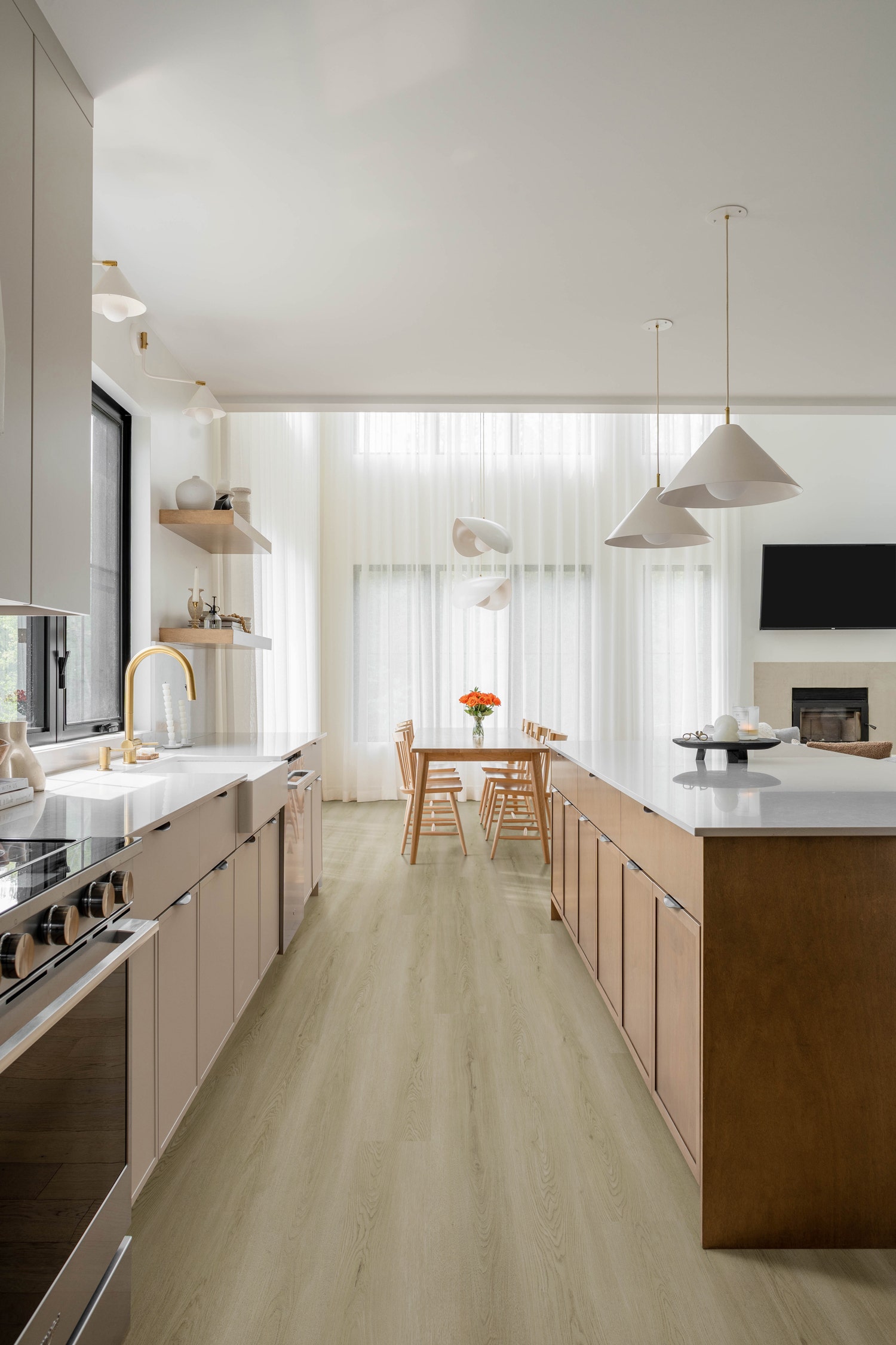 Evo Grey Oak Hybrid Textured Flooring Bright, modern kitchen and dining area showcasing Evo Grey Oak Hybrid Textured flooring, complemented by light wood cabinetry and sheer curtains.