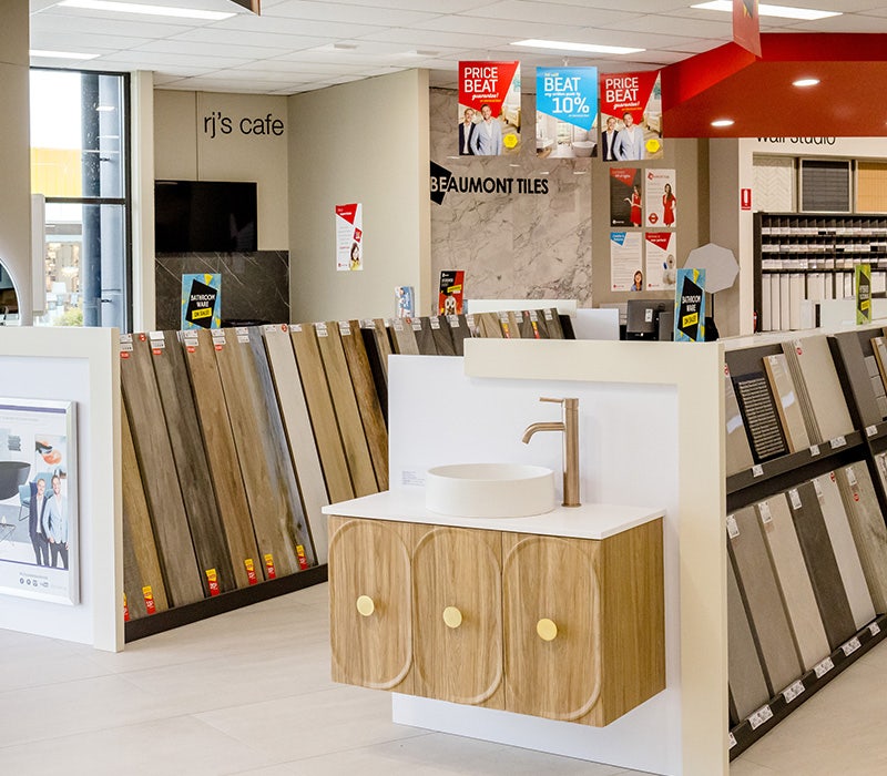 Beaumont Tiles store inside, tiles, a wooden vanity with white top, a white rounded basin, and gold tapware on display