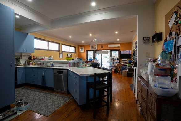 A dark and outdated kitchen and a living room with clutter all around