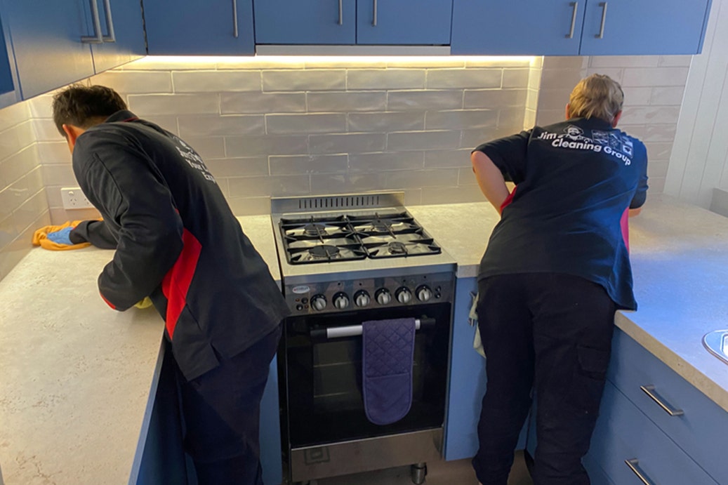 Two people cleaning the just renovated kitchen and splashback tiles