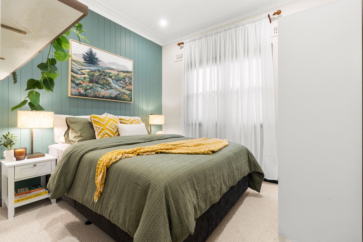 Bedroom with bed, nightstand, and painting on the wall.