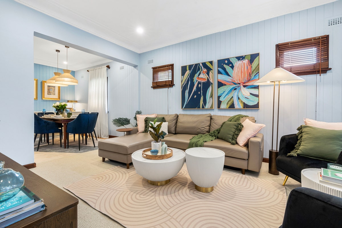Living room with modern furniture: couch, two coffee tables, two chairs, and three paintings.