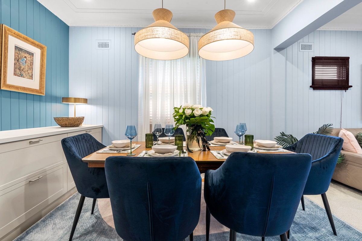 dining room set up with modern furniture, 6 chairs, and two hanging lamps.