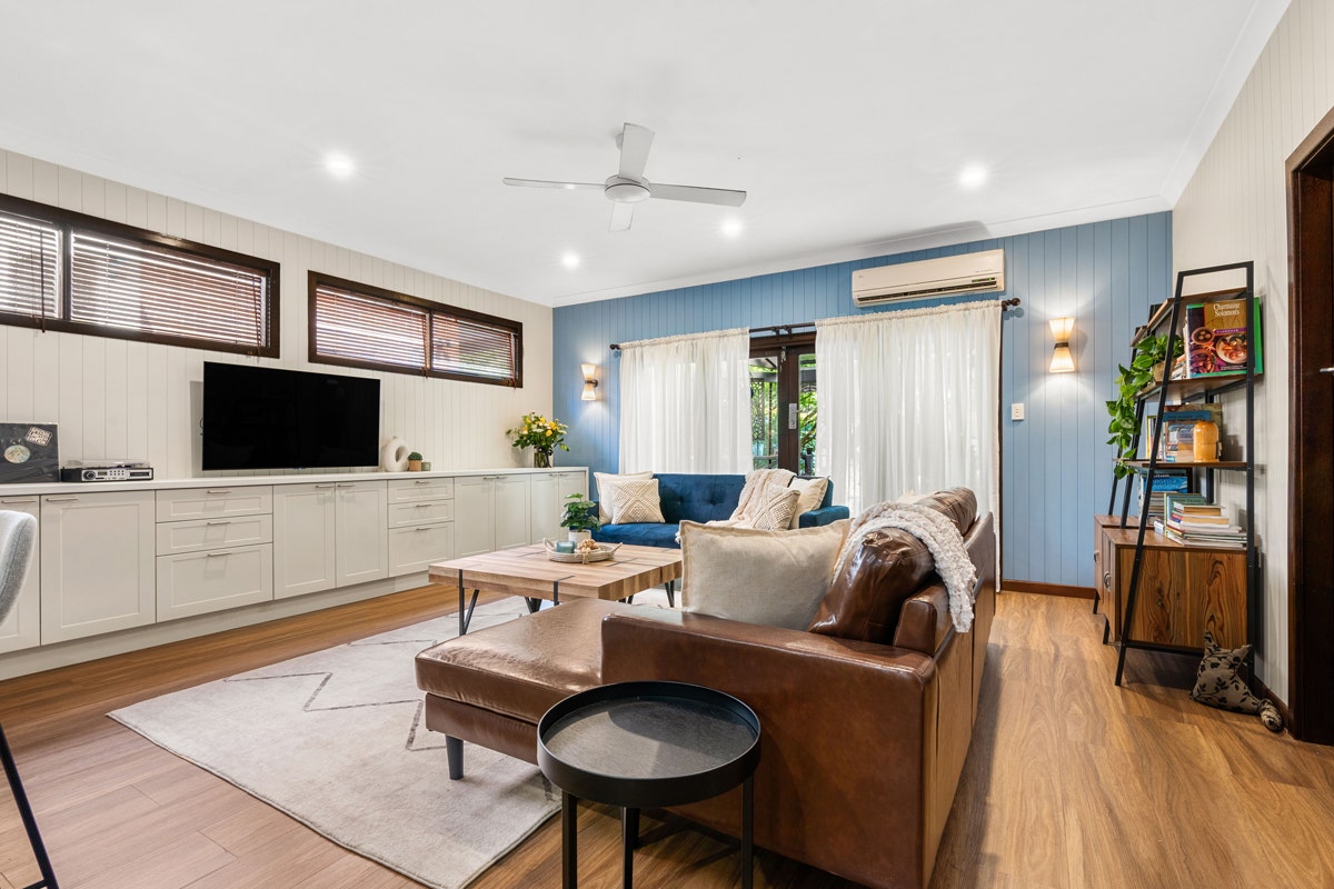 Living room with couch, coffee table, ceiling fan, and mounted TV.