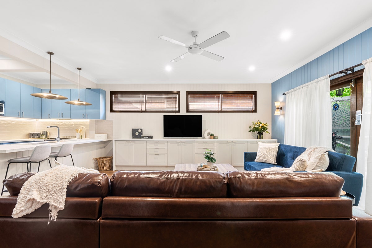 Living room with couch, coffee table, ceiling fan, and mounted TV.