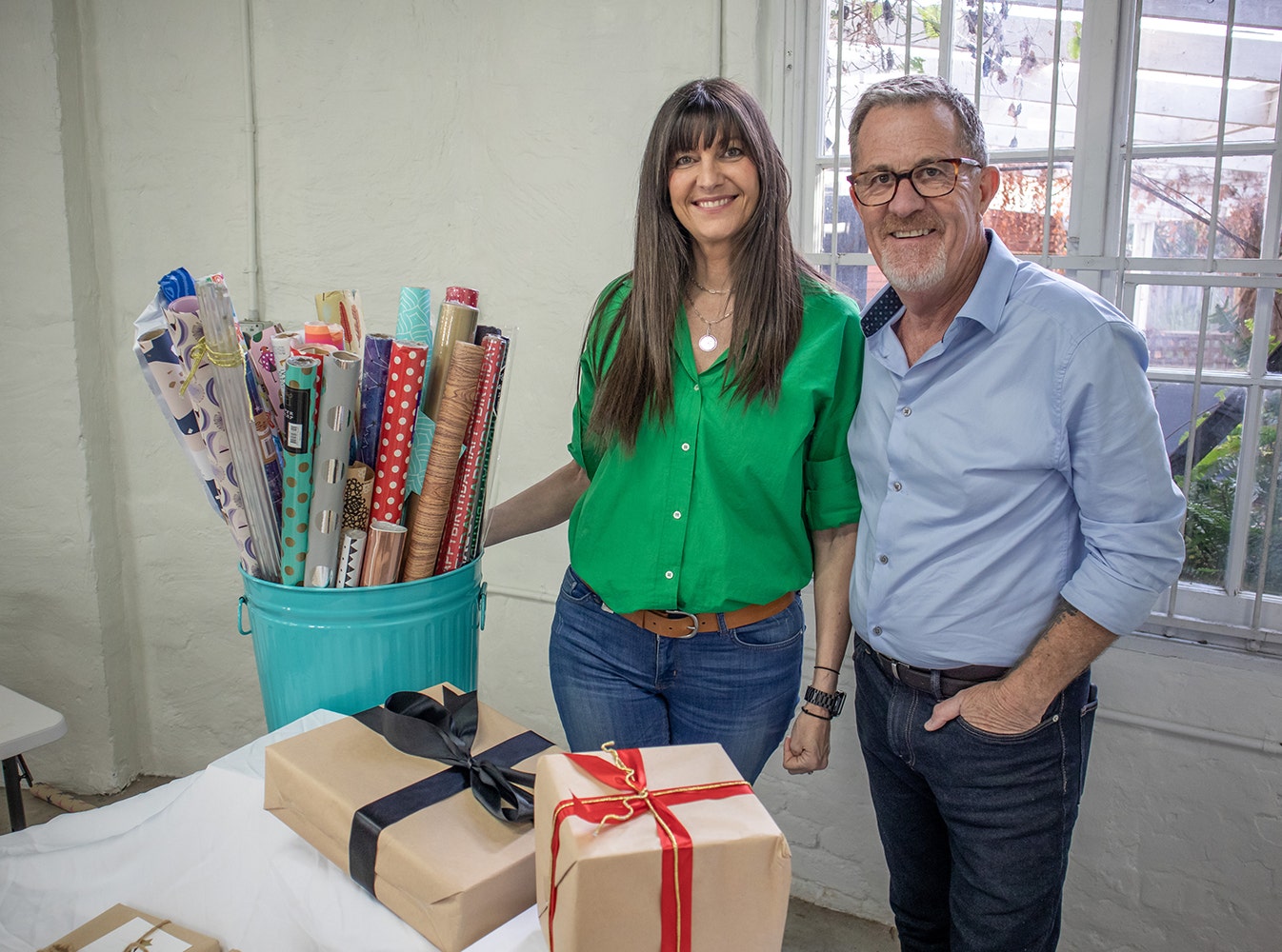 Peter and Jo smiling at the camera next to her wrapping gifts table