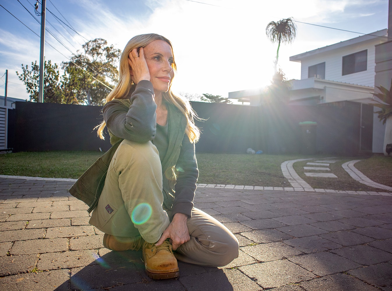 Inspirational image of Cherie sitting outdoors with a hand on her hair and looking away with the sunshine on her face