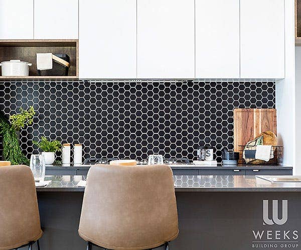 Stylish Kitchen with White Cabinets, Black Hexagonal Splashback Tiles, and Stools by the Kitchen Bench