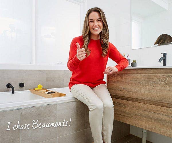 Happy Woman with Thumbs Up, Seated on a Bathtub, Leaning on a Vanity, and Text 'I Chose Beaumonts!'